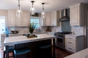 An updated kitchen with traditional cabinets and a large island with a marble countertop.