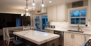 Updated kitchen with white cabinets, marble countertops, and center island