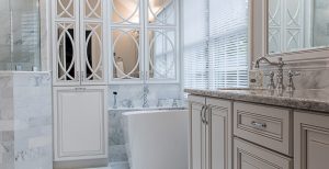 Modern bathroom with white cabinetry, standalone tub, and tiled walls