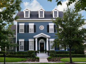 Blue two-story Colonial with white trim and well-kept landscaping